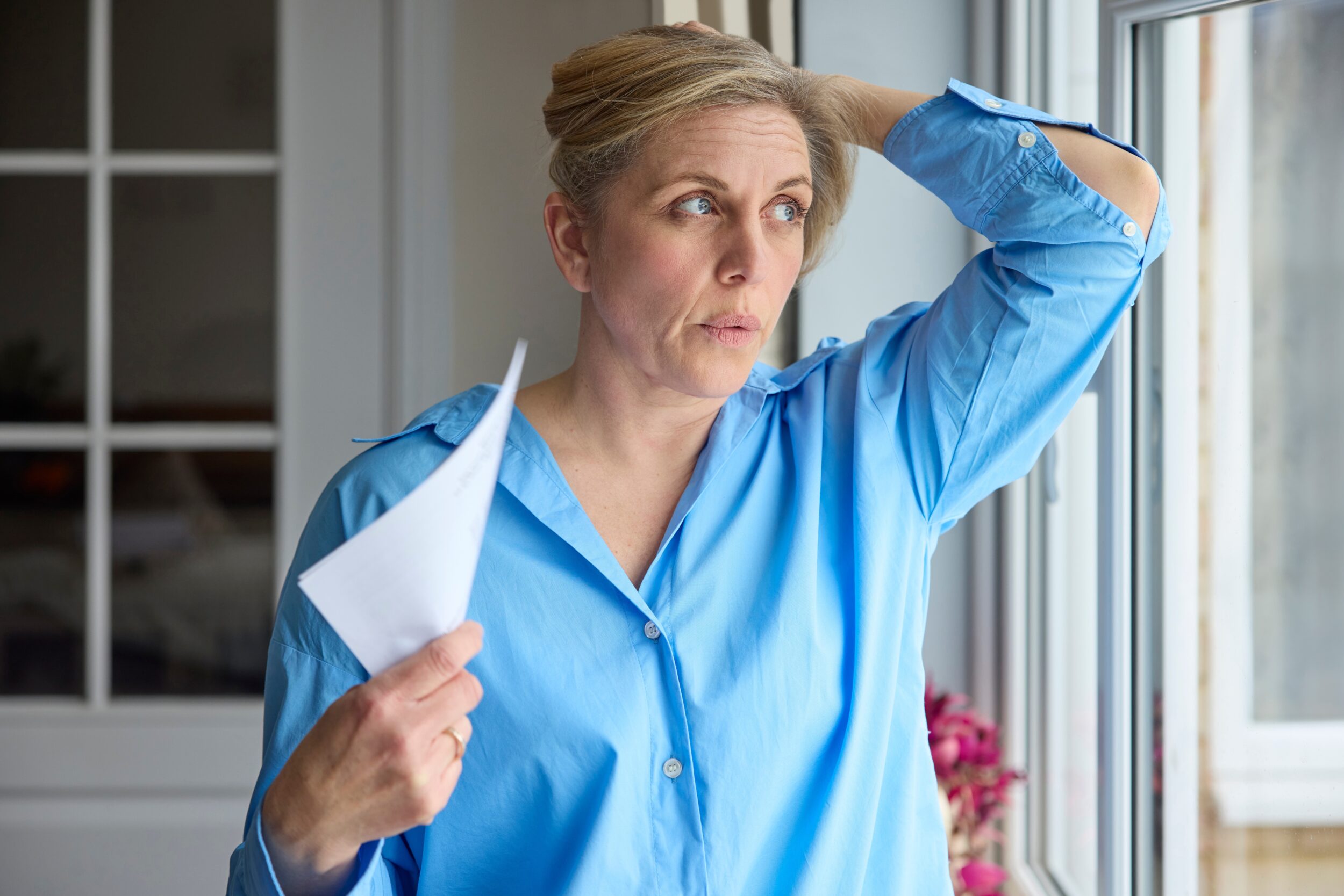 Middle-aged woman fanning herself during a menopause hot flash