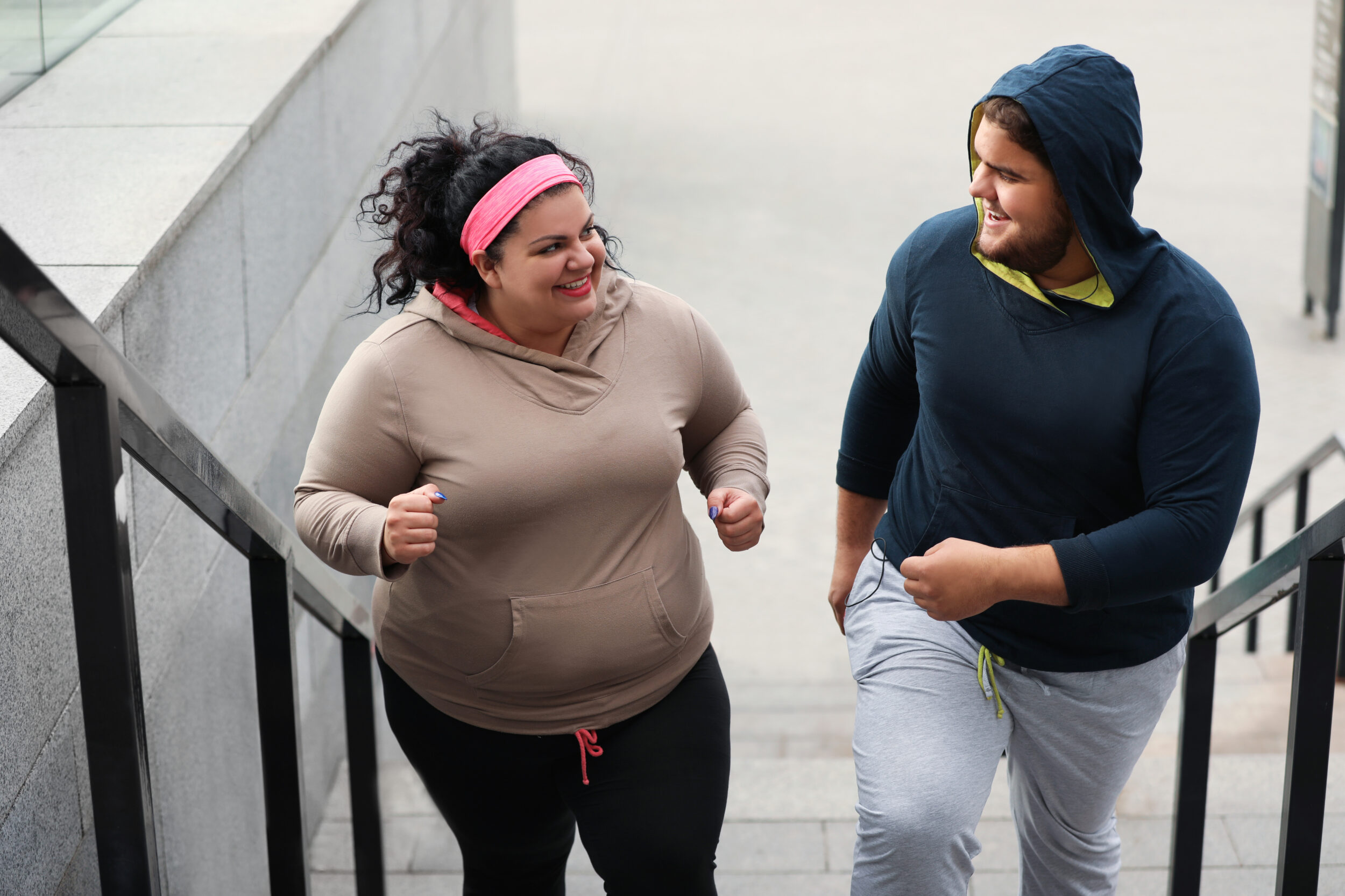 Man and woman in workout gear running up the stairs, trying to lose weight