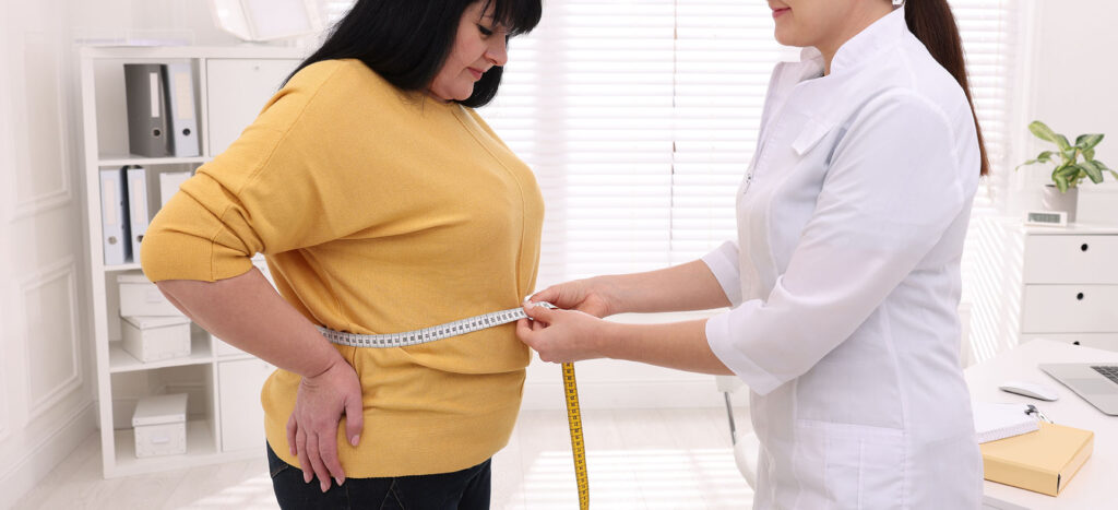 Nutritionist measuring overweight woman's waist with tape in cli Doctor measuring patient’s waist during medical weight loss consultation.