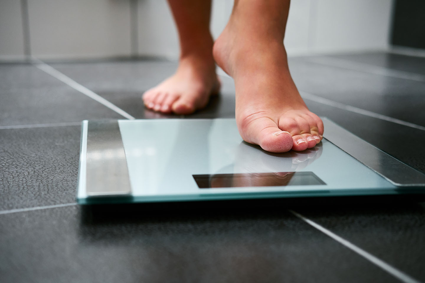 Person stepping on scale to track progress in medical weight loss.