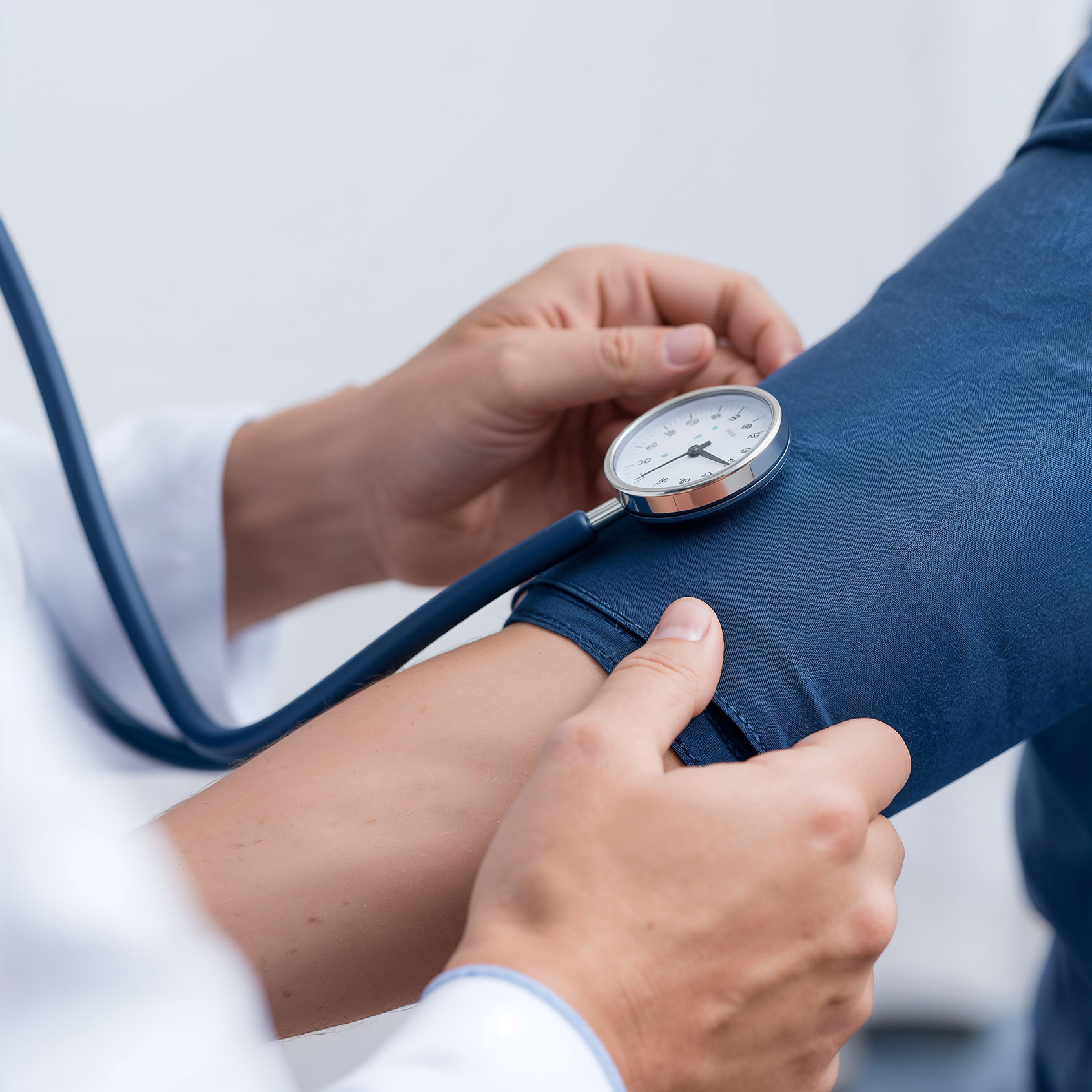 A doctor holds a manual blood pressure cuff on a patient’s arm while checking the gauge.