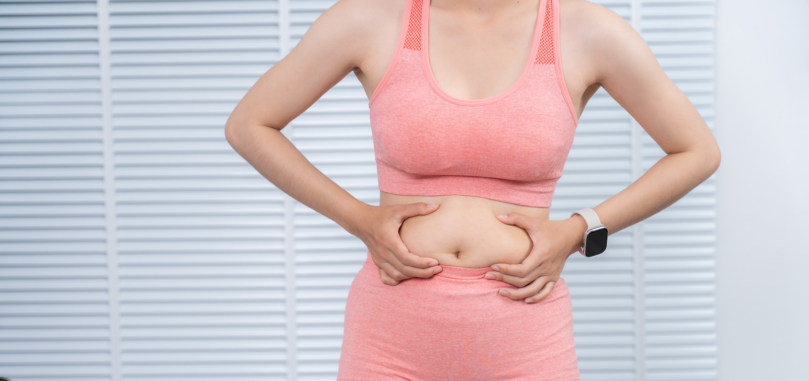 Midsection skin pinch view Person in athletic wear pinching skin at the lower abdomen