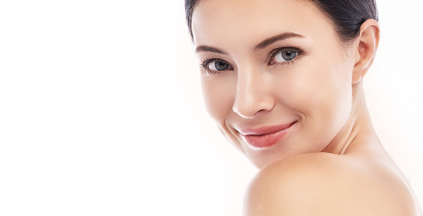 Woman with hair pulled back, facing camera, bare shoulders visible against a white background.