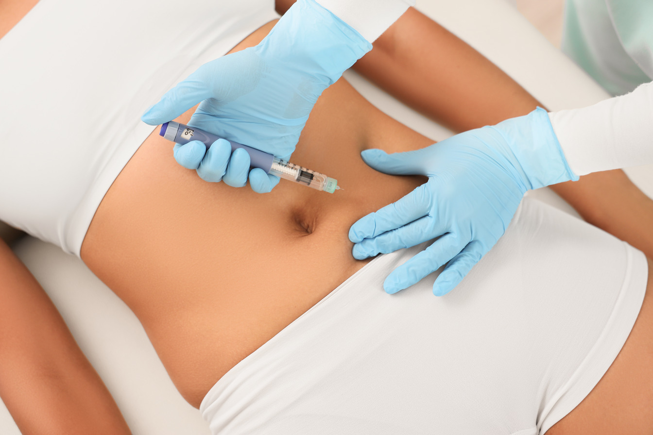 Man stands on a scale while a clinician reviews information on a clipboard nearby
